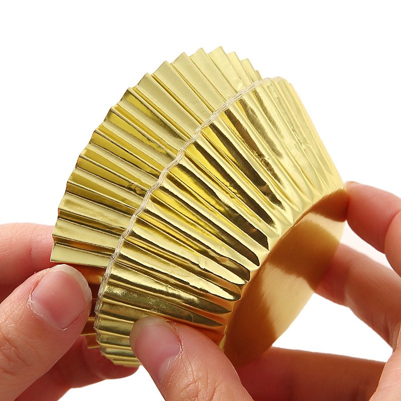 Gold Foil Muffin Cupcake Liners Hand holding gold foil cupcake liner – metallic baking cup with shiny finish for parties